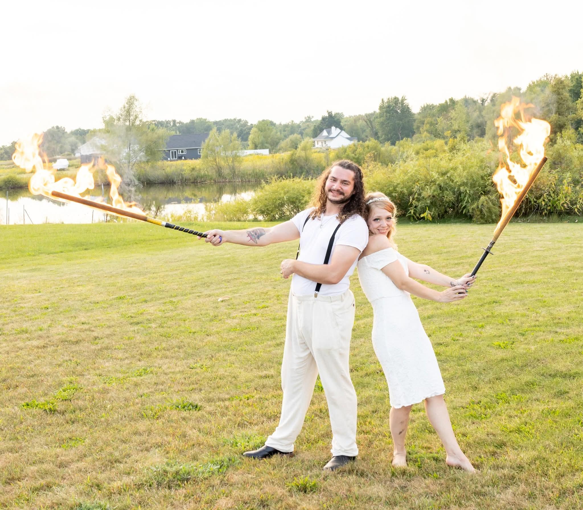 K and Ryan of Lakeland Cabaret posing back-to-back with flaming swords